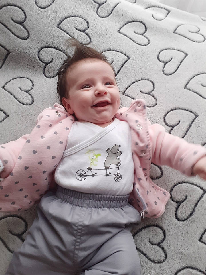 Sasha participe au concours pour gagner de l'argent avec cette photo : baby, baby_toddler_clothing, bedding, cheek, child, circle, comfort, face, happy, head, linens, pattern, person, pink, sitting, skin, sleeve, smile, textile, toddler