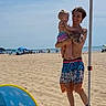 Zane is registered to the contest to win money with this photo: beach, baby, man, tattoos, holding, sand, ocean, sunny, tent, people, happy, child, summer, vacation, shore, outdoor, family, casual, clothing, blue_sky