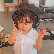 Ayane a rejoint le concours — aidez-le/la à gagner de superbes lots ! carpet, chair, child, curious, curly_hair, cushion, cute, expression, floor, furniture, headphones, home, indoor, living_room, person, shorts, standing, table, toddler, white_shirt