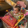 toddler, baby, child, activity_walker, toy_book, pigtails, indoor, nursery, playful, colorful, curious, plastic_toys, pink, seat, table, furniture, childrens_toy, mirror_toy, play_area, engaged