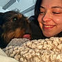 Tyson participe au concours pour gagner de l'argent avec cette photo : woman, dog, smiling, face, indoor, blanket, knitted_blanket, pet, affection, closeup, happy, cozy, cute, friendship, relaxation, casual, natural_light, brown_dog, black_hair, earring