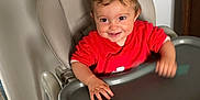 Manuel a rejoint le concours — aidez-le/la à gagner de superbes lots ! baby, child, cute, domestic, face, furniture, hand, happy, high_chair, home, indoor, person, playful, red_clothing, seat, smiling, toddler, tray_table, wooden_floor, young_child