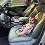 Aida is registered to the contest to win money with this photo: baby, child, car_interior, car_seat, leather_seat, infant, passenger_seat, window, sunlight, can, cup_holder, steering_wheel, dashboard, door, floor_mat, house, brick_wall, seatbelt, looking, sitting