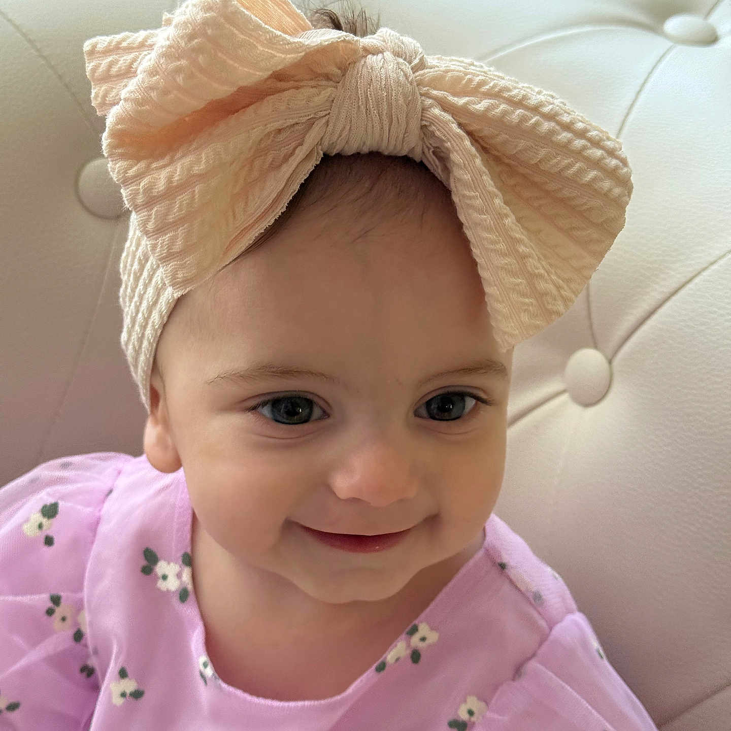 Aida is registered to the contest to win money with this photo: baby, bow, child, couch, cute, dress, eyes, face, fashion, floral, happy, headband, indoors, person, portrait, purple, smile, soft_light, toddler, upholstery