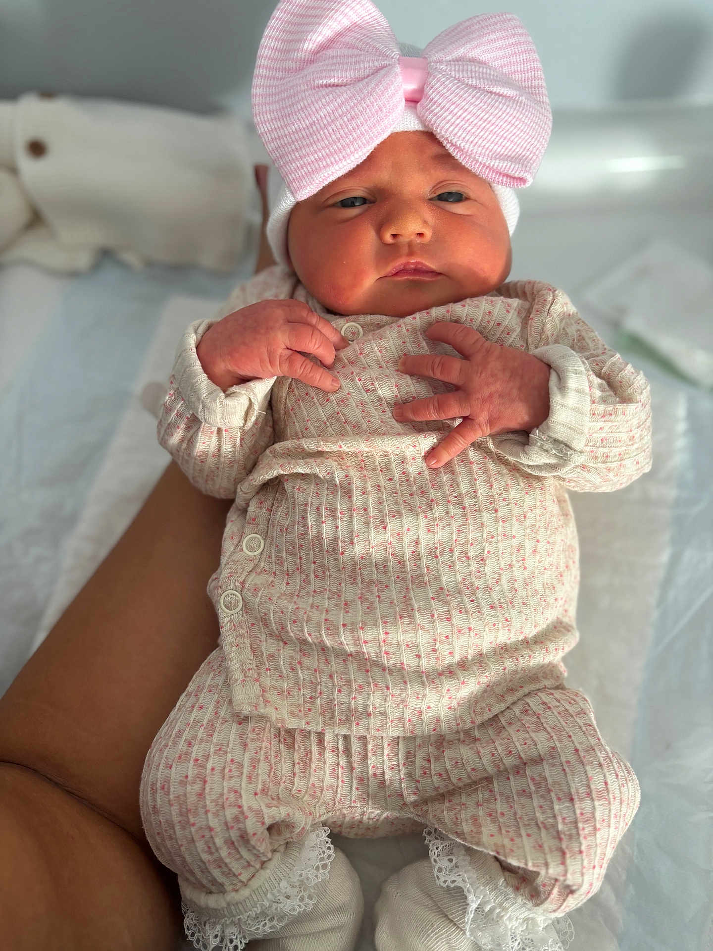Mïa a rejoint le concours — aidez-le/la à gagner de superbes lots ! baby, infant, pink_bow, hat, knit_clothing, hands, legs, white_socks, lace, person, indoor, soft_light, skin, cute, newborn, lying_down, closeup, comfort, supporting_arm, warm_tone