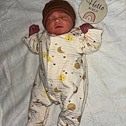 Mïa a rejoint le concours — aidez-le/la à gagner de superbes lots ! newborn, baby, sleeping, onesie, hat, blanket, soft, cute, sign, hello_world, rainbow, infant, cozy, patterned_clothing, peaceful, lying_down, indoors, portrait, child, face