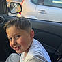 child, boy, smile, lollipop, car_interior, tshirt, seat, window, side_mirror, parking_lot, daylight, short_hair, casual, seatbelt, vehicle, happy, portrait, young, cute, inside_car
