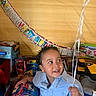 toddler, child, birthday, balloon, toy, curly_hair, blue_shirt, indoor, party, smiling, decorations, present, spiderman, truck, soccer, happy, face, hand, celebration, gift