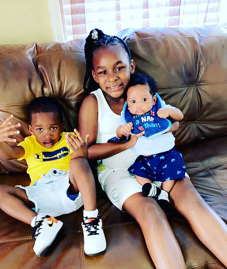 Zaniyah joined the competition — help win amazing prizes! baby, baby_toddler_clothing, child, comfort, couch, facial_expression, fun, furniture, happy, human_leg, joy, lap, leg, living_room, mammal, person, sitting, skin, smile, t_shirt