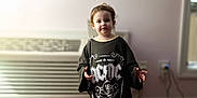Scarlet joined the competition — help win amazing prizes! child, toddler, portrait, indoor, standing, carpet, air_conditioner, oversized_tshirt, band_tshirt, acdc_logo, smile, face, hands, pink_wall, window_blinds, power_cord, outlet, bokeh, soft_light, home_interior