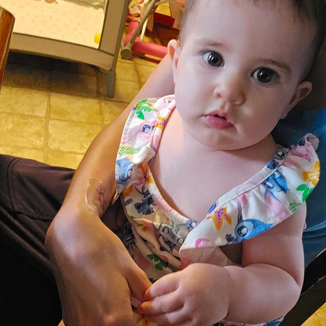 Scarlet joined the competition — help win amazing prizes! adult, baby, child, curious, eyes, face, floor, furniture, hand, high_chair, holding, home, indoor, infant, person, playpen, romper, seated, skin, wooden_cabinets