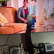 Sussie is registered to the contest to win money with this photo: cat, black_cat, television, woman, sofa, plant, couch, indoor, shelf, photograph_frames, curious, silhouette, subtitles, living_room, decor, lamp, glass_table, home, entertainment, animal