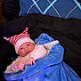 baby, bed, blanket, blue_blanket, child, comforter, cozy, cute, hat, indoors, infant, lying_down, newborn, pillow, red_and_white, resting, sleepwear, soft_texture, striped_hat, warm