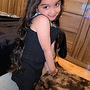 Hajrah joined the competition — help win amazing prizes! child, girl, black_dress, long_hair, bow, smile, indoor, carpet, wooden_cabinet, furniture, posing, cute, portrait, stockings, happy, young, fashion, home, floor, room