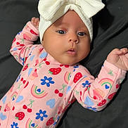 Aurora is registered to the contest to win money with this photo: baby, infant, child, portrait, lying_down, bed, bow_headband, pink_outfit, patterned_clothing, strawberries, flowers, rainbows, hearts, wide_eyes, surprised_expression, arms_raised, indoor, close_up, cute, photography