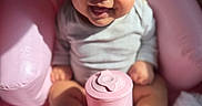 Aurora joined the competition — help win amazing prizes! baby, infant, child, smiling, sitting, portrait, pink, chair, cup, container, indoor, close_up, face, eyes, hair, shirt, barefoot, legs, happy, photography