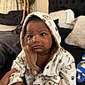 Jiovonni joined the competition — help win amazing prizes! baby, infant, child, hooded_outfit, onesie, bear_pattern, sitting, portrait, face, eyes, serious_expression, indoor, bedroom, couch, pillows, blanket, soft_fabric, adult_hand, home, photography