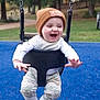 toddler, child, swing, playground, blue_surface, beanie, hat, smiling, happy, outdoor, park, trees, grass, clothing, baby, seat, fun, joy, play, nature