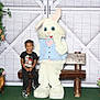 child, easter_bunny, mascot, bench, flowers, plant, pot, decoration, smile, happy, indoor, costume, holiday, spring, greenery, wood, carpet, person, cute, celebration