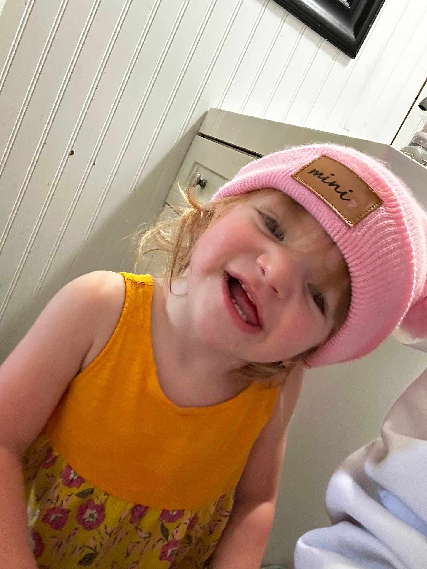 Ruby joined the competition — help win amazing prizes! toddler, child, pink_hat, yellow_dress, smiling, indoor, cabinet, face, person, cute, happy, portrait, headwear, clothing, skin, hair, expression, baby, room, playful