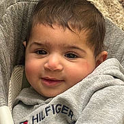 Isabella joined the competition — help win amazing prizes! baby, child, face, smile, hoodie, clothing, grey, person, young_child, cute, indoor, portrait, seated, furniture, fabric, cozy, hair, skin, eyebrows, eyes