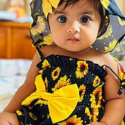 Violet joined the competition — help win amazing prizes! baby, child, sunflower, hat, yellow_bow, dress, cute, portrait, indoors, sitting, infant, face, eyes, skin, hand, clothing, headwear, patterned_clothing, closeup, adorable