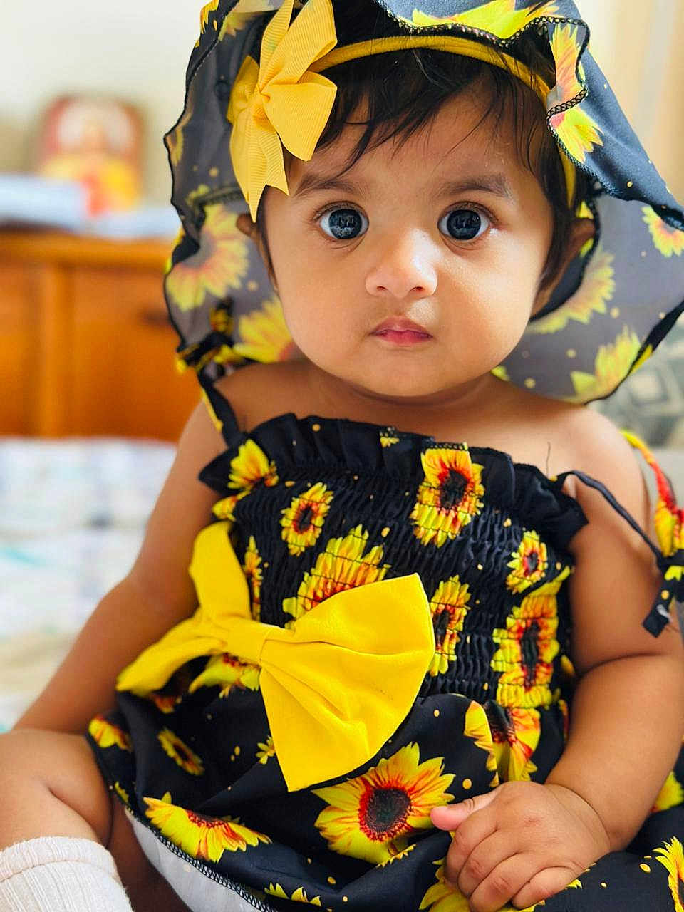 Violet joined the competition — help win amazing prizes! baby, child, sunflower, hat, yellow_bow, dress, cute, portrait, indoors, sitting, infant, face, eyes, skin, hand, clothing, headwear, patterned_clothing, closeup, adorable