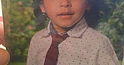 Michael joined the competition — help win amazing prizes! child, school_portrait, curly_hair, shirt, tie, collar, portrait, smiling, looking_at_camera, garden, flowers, greenery, printed_photo, photograph, indoor, year_text, school, formal_wear, headshot, face