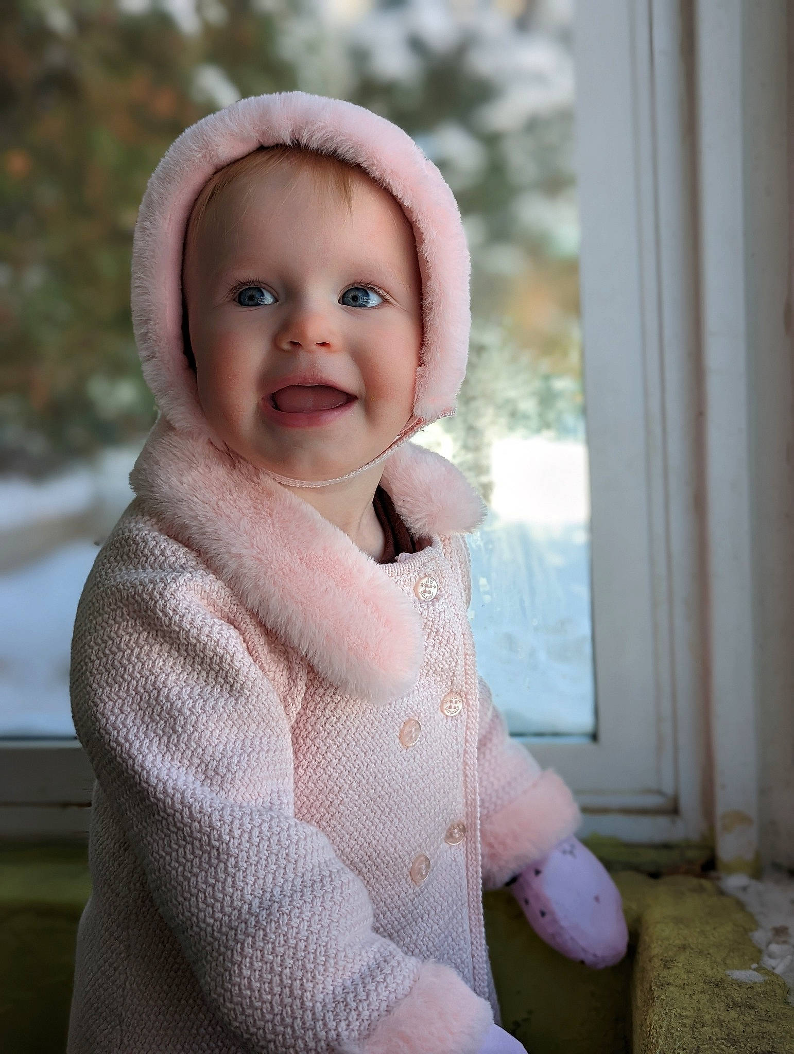 Willa is registered to the contest to win money with this photo: baby, baby_toddler_clothing, cap, cheek, child, fur, grass, happy, joy, laugh, lip, outerwear, pattern, person, skin, sleeve, smile, standing, toddler, window