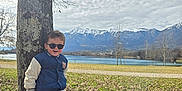 Preston a rejoint le concours — aidez-le/la à gagner de superbes lots ! child, boy, sunglasses, tree, tree_trunk, jacket, cargo_pants, boots, park, lake, mountains, snow_capped_mountains, sky, clouds, grass, fallen_leaves, smile, portrait, outdoors, sunlight