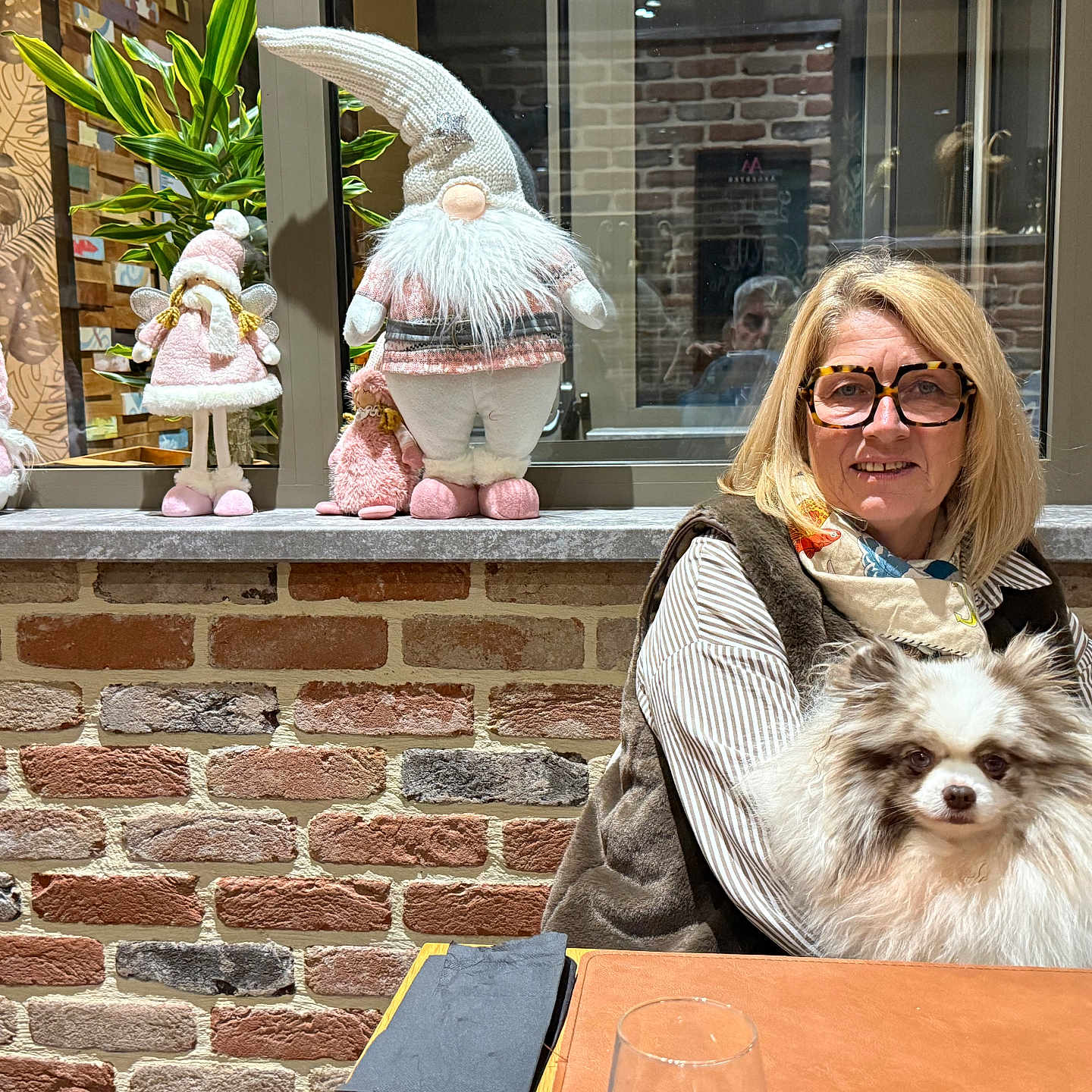Christelle Debove a rejoint le concours — aidez-le/la à gagner de superbes lots ! brick_wall, casual_clothing, cozy, decorations, dog, fur, glasses, gnomes, hair, indoor, pet, plant, portrait, reflection, scarf, seated, smile, table, window, woman