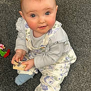 Coralie joined the competition — help win amazing prizes! baby, child, carpet, toy, wooden_toy, blue_socks, overalls, floral, playthings, indoor, cute, smiling, curious, sitting, infant, face, hands, clothing, person, floor
