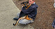 Precious joined the competition — help win amazing prizes! animal, casual_clothing, companion, daylight, dog, friendship, greenery, hugging, man, mulch, nature, outdoor, people, pet, plants, relaxation, rocks, shoes, sidewalk, urban