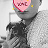 Winnie a rejoint le concours — aidez-le/la à gagner de superbes lots ! person, puppy, dog, black_and_white, heart_sticker, love, hand, fuzzy_jacket, portrait, indoor, close_up, cute, affection, cuddle, young_adult, face_cover, warm, soft_texture, animal, pet