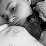 person, dog, bed, blanket, sleeping, snuggling, face, closeup, cozy, resting, indoor, black_and_white, hair, comfort, cuddle, pet, animal, fur, relaxation, portrait