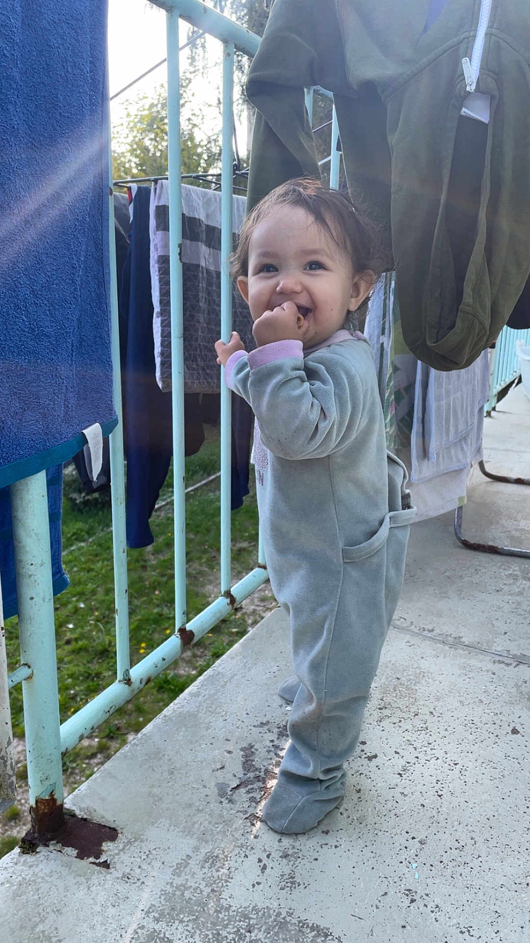 Kayla a rejoint le concours — aidez-le/la à gagner de superbes lots ! toddler, child, baby, balcony, clothing, laundry, railing, outdoor, smiling, snack, footwear, daylight, playful, casual, portrait, person, happy, curly_hair, concrete_floor, jumpsuit
