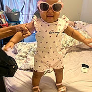 Sarya is registered to the contest to win money with this photo: toddler, child, sunglasses, pink, standing, bed, hand, support, clothing, footwear, indoor, blanket, window, curtain, person, smile, happy, home, cute, accessory