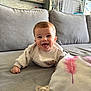 baby, child, couch, cute, face, furniture, gray_sofa, happy, home, indoor, infant, living_room, pacifier, person, pillow, pink_feather, relaxed, smiling, sweater, young_child