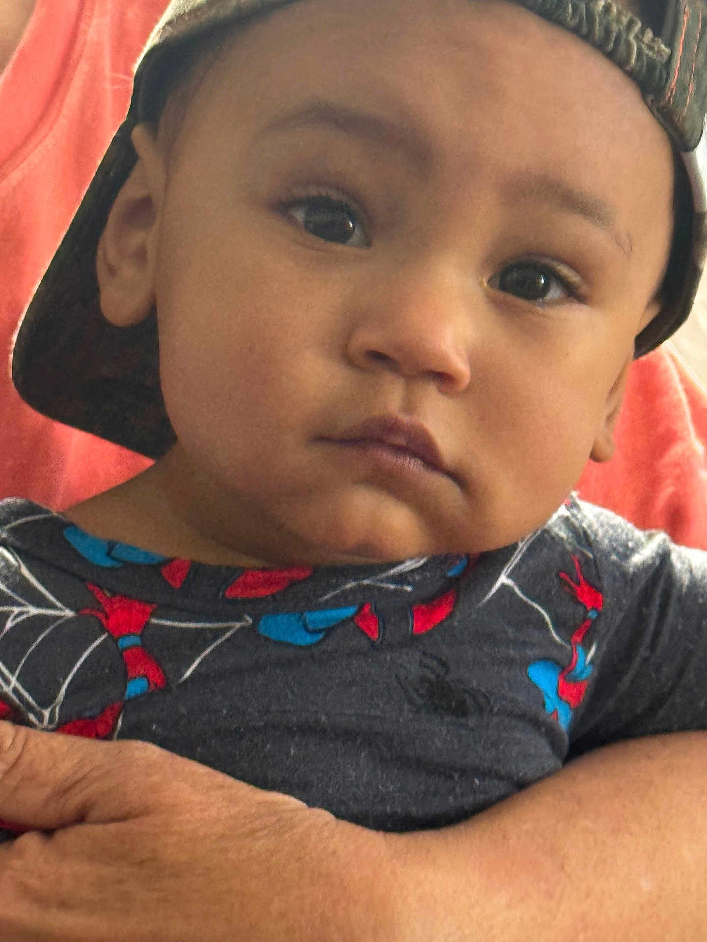 Callen is registered to the contest to win money with this photo: toddler, child, face, cap, hat, spiderman, shirt, clothing, arm, hand, person, closeup, indoors, expression, serious, young_child, portrait, skin, headwear, background