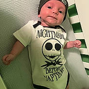 Waylon Hood joined the competition — help win amazing prizes! baby, infant, crib, onesie, hat, face, person, clothing, bed, sleepwear, cute, expression, child, newborn, smile, indoors, text_on_clothing, blanket, rest, naptime