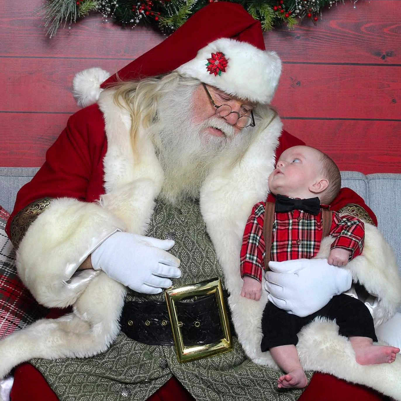 Waylon Hood is registered to the contest to win money with this photo: adult, baby, beard, berries, bow_tie, child, christmas, couch, decorations, festive, glasses, gloves, holiday, indoor, plaid_shirt, portrait, red_suit, santa_claus, white_fur, wreath