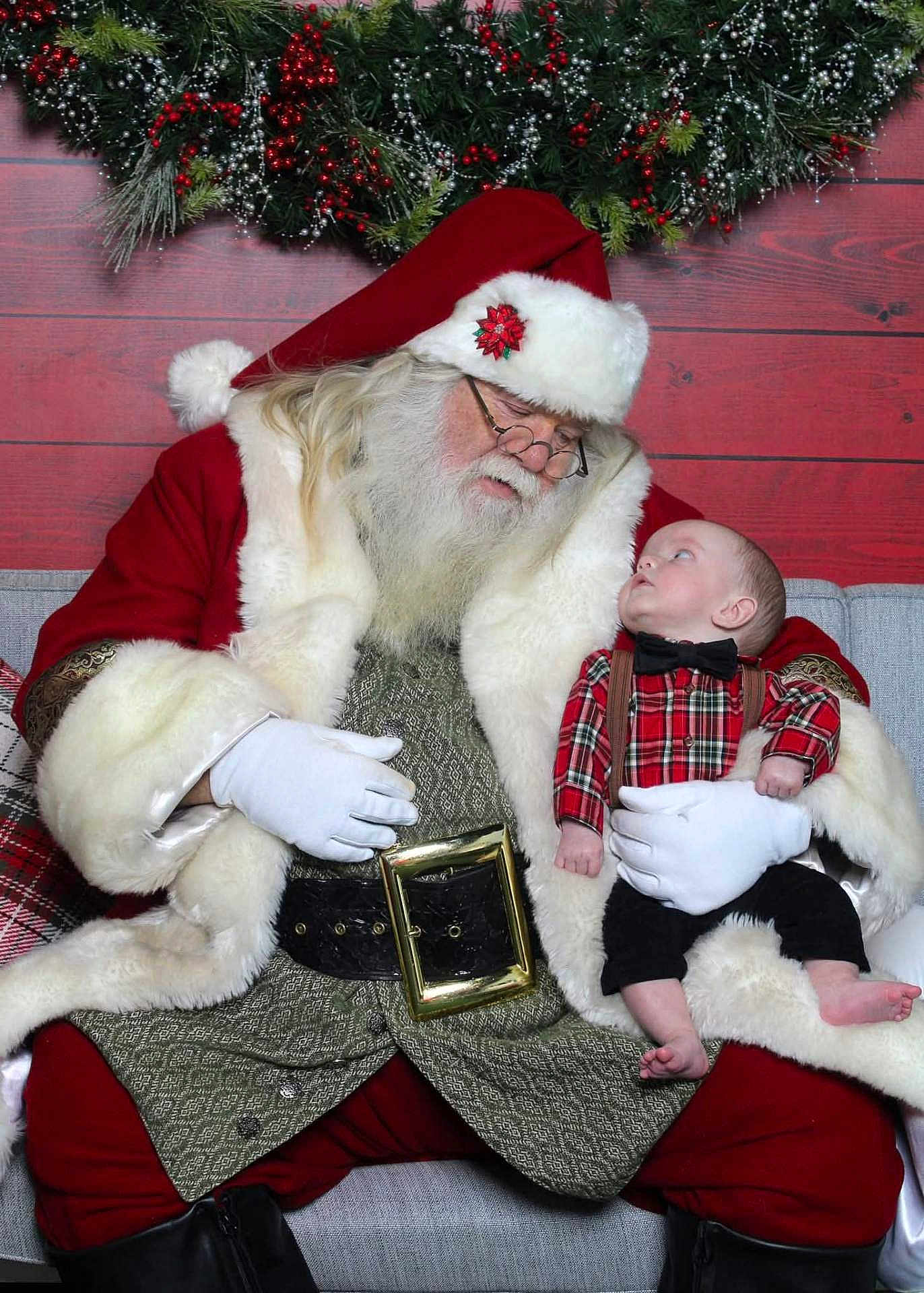 Waylon Hood is registered to the contest to win money with this photo: santa_claus, baby, christmas, holiday, plaid_shirt, bow_tie, red_suit, white_fur, wreath, berries, glasses, gloves, beard, couch, festive, indoor, decorations, child, adult, portrait