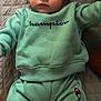 Waylon Hood is registered to the contest to win money with this photo: baby, child, infant, face, clothing, sweatshirt, pants, socks, green, champion, portrait, indoor, laying_down, quilted_blanket, cute, young, person, apparel, looking, expression