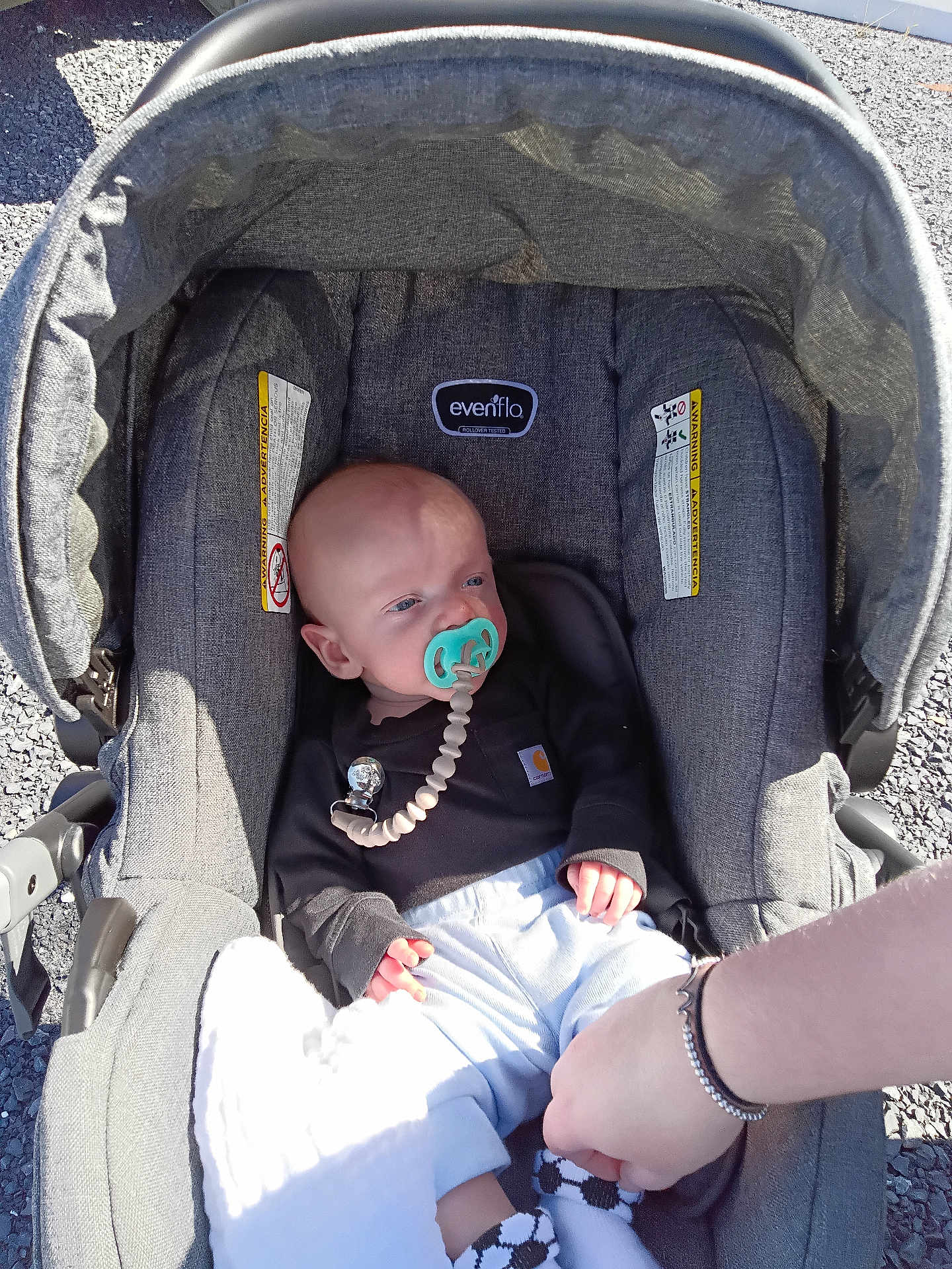 Waylon Hood is registered to the contest to win money with this photo: baby, pacifier, car_seat, evenflo, clothing, socks, hand, person, infant, outdoor, sunlight, asphalt, gray, comfort, baby_clothes, bracelet, footwear, toy_clip, seat, portrait