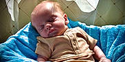 Waylon Hood is registered to the contest to win money with this photo: baby, blanket, blue_blanket, child, clothing, comfort, cozy, curtain, face, head, indoors, infant, onesie, patterned_curtain, peaceful, portrait, resting, skin, sleeping, soft_light