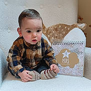 Amaël participe au concours pour gagner de l'argent avec cette photo : baby, calendar, chair, child, cozy, curious, cute, furniture, home, indoor, infant, milestone, person, plaid_shirt, plush_pillow, portrait, sitting, socks, soft_lighting, warm_tones