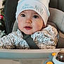 baby, child, hat, high_chair, christmas_tree, holiday, festive, face, eyes, infant, seatbelt, clothing, indoors, toy, curious, portrait, cute, winter, smile, decorations