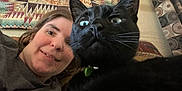 Midnight is registered to the contest to win money with this photo: woman, cat, black_cat, face, pet, indoor, selfie, tapestry, curtain, furniture, pattern, close_up, whiskers, collar, home, portrait, expression, looking, cozy, casual