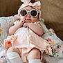 baby, infant, sunglasses, headband, bow, blanket, floral_pattern, sitting, cute, fashion, clothing, white_socks, soft_lighting, portrait, indoor, couch, smile, hands, legs, skin