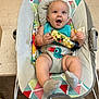 baby, infant, baby_seat, popcorn, toy, colorful, patterned, happy, smiling, indoor, floor, carpet, clothing, socks, face, child, cute, playful, seated, holding